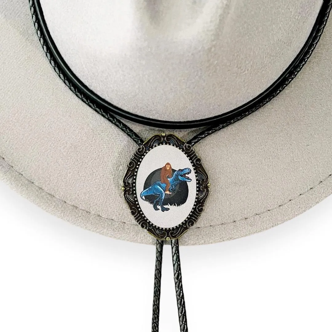 Bolo Tie with Bigfoot -  Bolo Ties with Big Foot Riding a Dinosaur T Rex in Black and Blue
