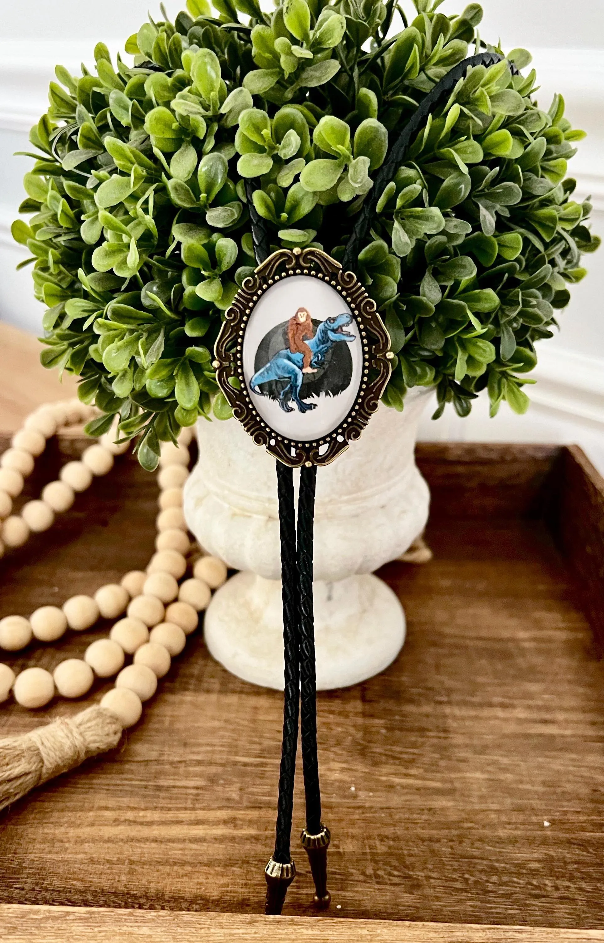Bolo Tie with Bigfoot -  Bolo Ties with Big Foot Riding a Dinosaur T Rex in Black and Blue
